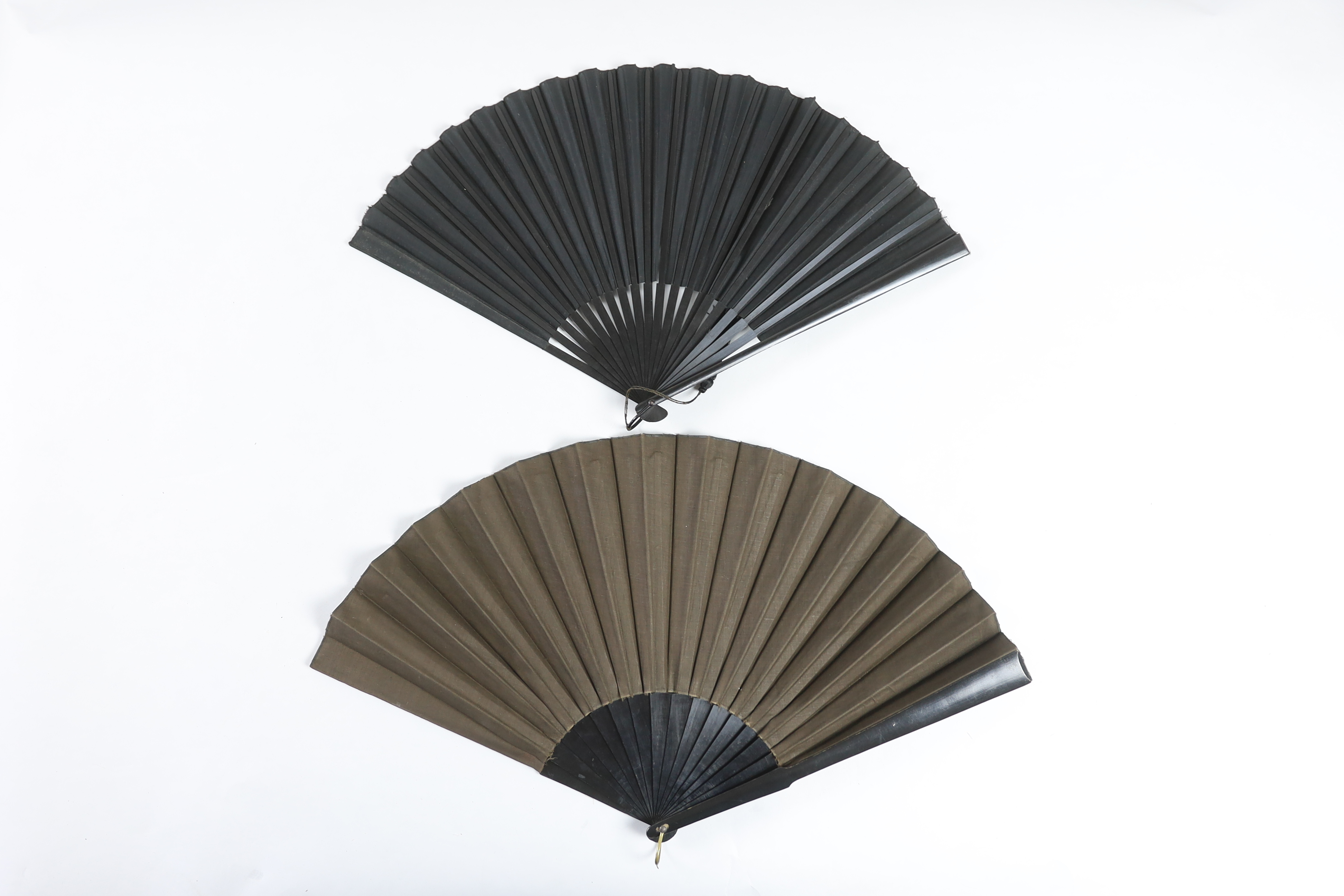 Two early 20th century ebony fans, one cotton leaf, the other hand painted pansies on a fine a silk leaf